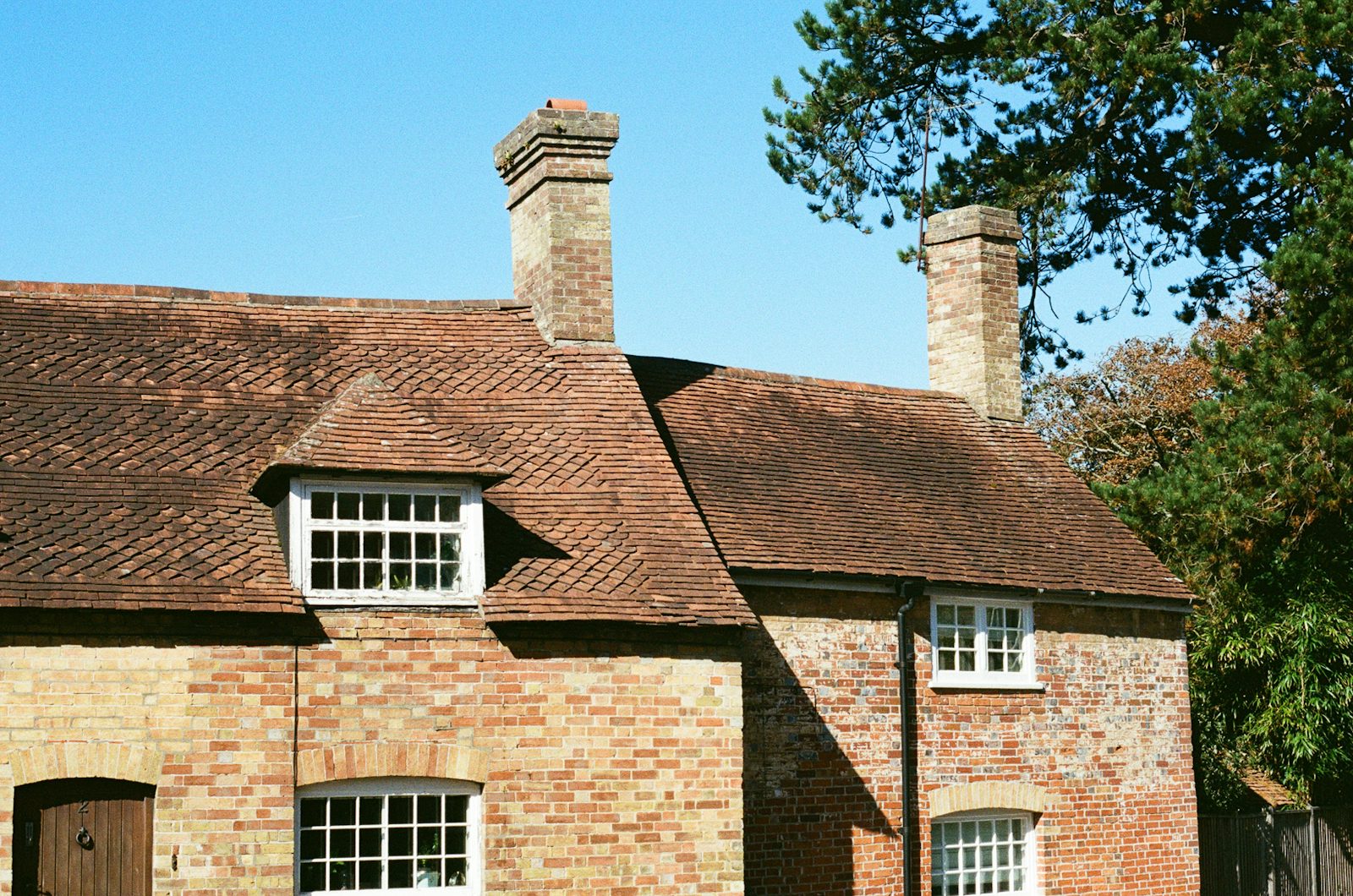 Restored clay tiled roof and rebuilt chimney stacks on a traditional British brick cottage