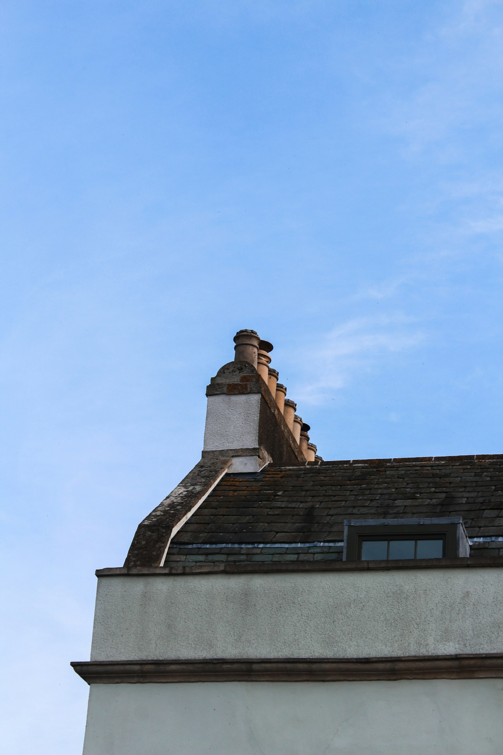 Rebuilt brick chimney stack with new pots and flaunching against a clear blue sky