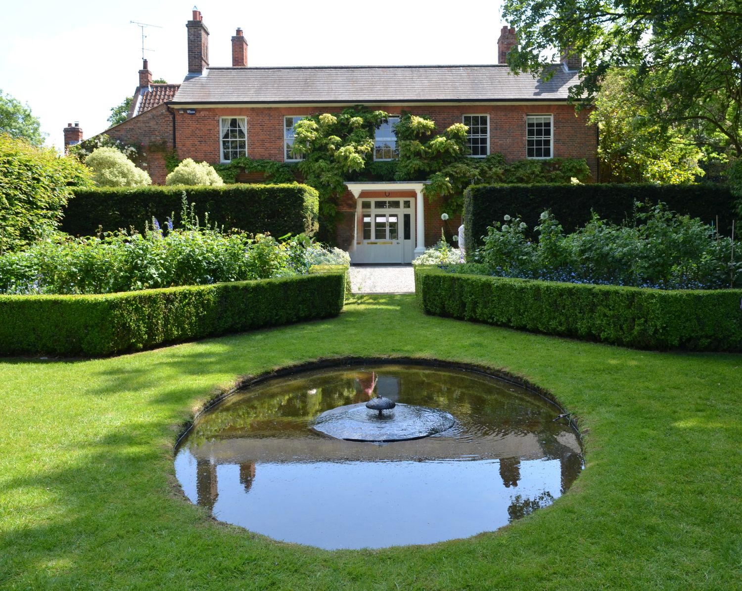 Country house garden with clipped hedging, lawn and an ornamental pond